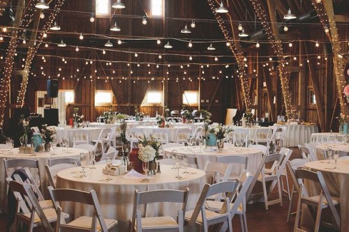 cover pillars and wooden beams with string lights to make your wedding venue shine in a creative way and to highlight the architecture of the space