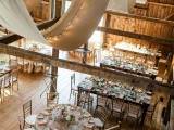 curtains and string lights hanging over the wodoen beams will give a lovely barn wedding venue a veyr cozy and elegant feel