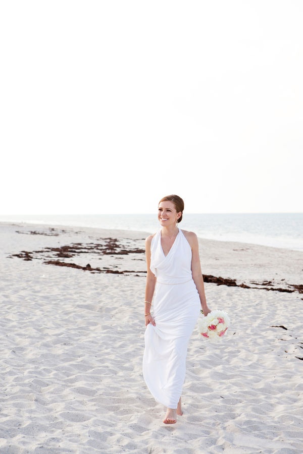 A modern white draped sheath wedding dress and bare feet for an elegant and stylish bridal look