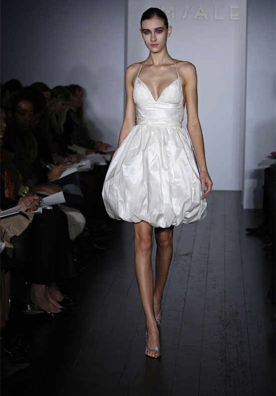 A whimsy short wedding dress of a shiny fabric, with spaghetti straps and a draped skirt
