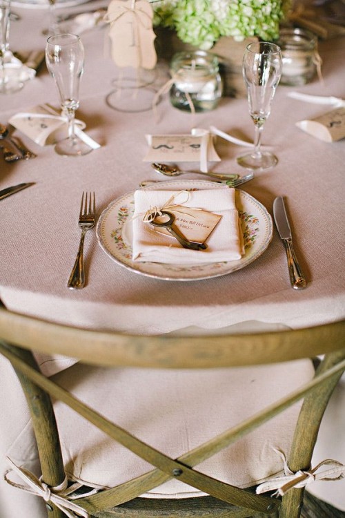 a neutral barn wedding table with simple linens, green hydrangeas, elegant cutlery and glasses