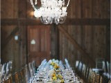 a vintage barn wedding tablescape with brown napkins, white and yellow blooms and greenery and all-neutral everything