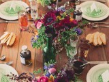 a colorful barn wedding tablescape with an uncovered table, colorful blooms, bright napkins, plates and glasses