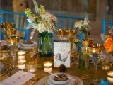 a bright barn wedding table with a burlap runner, neutral napkins, gold cutlery and gold rimmed glasses, neutral blooms and votives