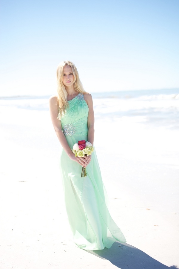 A light green maxi bridesmaid dress with embellishments on the shoulder and waist for a pastel beach wedding