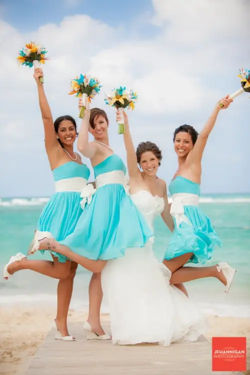 bright turquoise A-line bridesmaid dresses with white sashes and white shoes for a bold beach wedding
