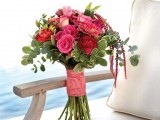 a colorful summer wedding bouquet of pink and burgundy blooms, greenery, lisianthus and a pink wrap is amazing for a bold summer wedding