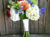 a bright summer wedding of white hydrangeas, orange pincushion proteas, purple blooms and greenery for summer