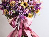 a bright wedding bouquet of pansies, lilac, purple and yellow ones, with a pink ribbon bow is a lovely idea for a summer celebration