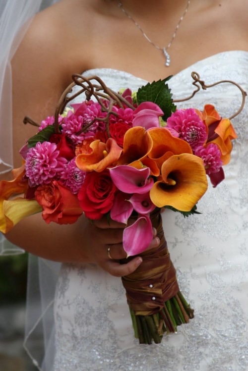 a bright wedding bouquet with yellow and pink callas, pink dahlias, greenery and twigs is an eye-catchy idea for a bold wedding