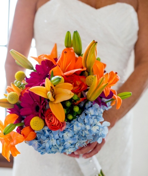 a bright summer wedding bouquet of orange lilies, burgundy gerberas, billy balls and blue hydrangeas is a bright and eye-catchy idea