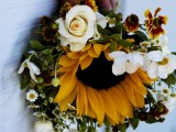 a catchy rustic wedding bouquet of a sunflower, white blooms around it and a bit of greenery is an arrangement that is simple to repeat