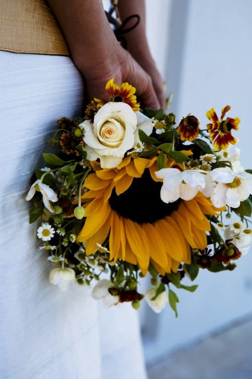 a catchy rustic wedding bouquet of a sunflower, white blooms around it and a bit of greenery is an arrangement that is simple to repeat