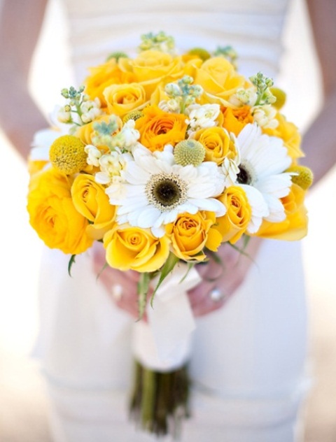 a bold wedding bouquet composed of yellow roses, billy balls and white blooms and greenery is amazing for spring or summer
