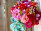 a bold wedding bouquet of light and hot pink and red blooms and greenery plus a turquoise ribbon wrap is a lovely solution for a colorful wedding
