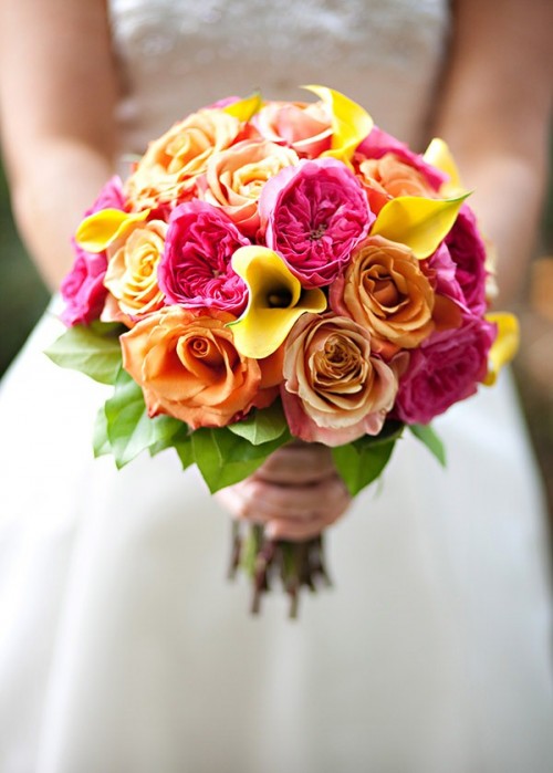 a wedding bouquet of hot pink peony roses, yellow callas, orange roses and leaves is a cool idea for a summer wedding