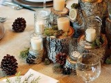 a cozy rustic Christmas tablescape with a burlap tablecloth, tree stumps with candles, pinecones and moss, gold chargers and greenery on each place setting