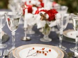a chic grey and red Christmas tablescape with red and white blooms, marble chargers, berries and sivler cutlery and silver glasses