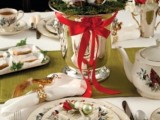 a red, green and white Christmas tablescape with a green runner, a Christmas tree in a vase, white and red blooms and minni ornaments