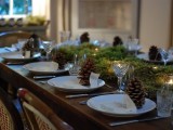 a natural Christmas table with moss and candles, pinecones, white porcelain and elegant glasses