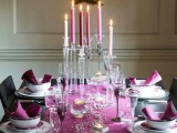 a bright Christmas tablescape with fuchsia napkins and a runner, tall and thin candles, mercury glass candleholders and printed floral porcelain
