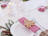 a homey Christmas wedding table with candles, plaid napkins, evergreens, cinnamon bark, gingerbread cookies and bloom centerpieces