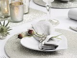 a neutral and shiny palce setting with glitter placemats and runners, thistles, dried blooms and mercury glass candleholders