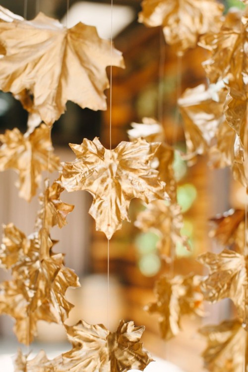 garlands of gold faux leaves hanging down compose a unique and beautiful fall wedding backdrop, you can DIY it and save the budget