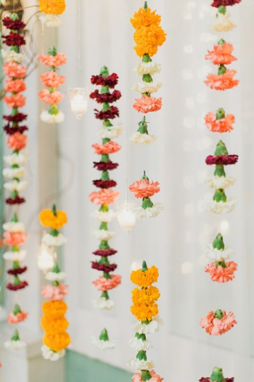 vertical garlands of bright carnations hanging down is a pretty and easy wedding decor idea, and you can make a backdrop of them
