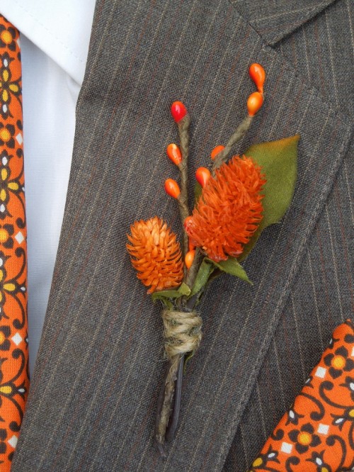 a bold fall wedding boutonniere with faux berries and bright orange blooms plus a leaf for a rustic fall wedding