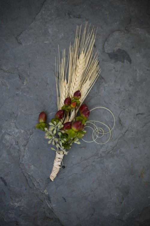 a lovely fall wedding boutonniere with spikes, berries and greenery and twine wrap for a rustic fall wedding look