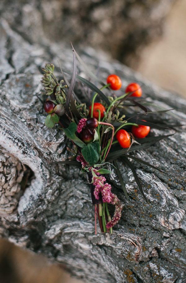 a boho fall wedding boutonniere with berries, nuts, greenery and blooms and grasses is amazing