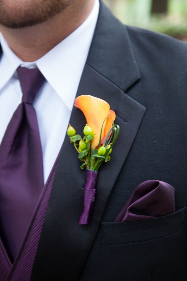 a bright wedding boutonniere with an orange calla and green berries plus grasses is a stylish and bold idea for a fall groom