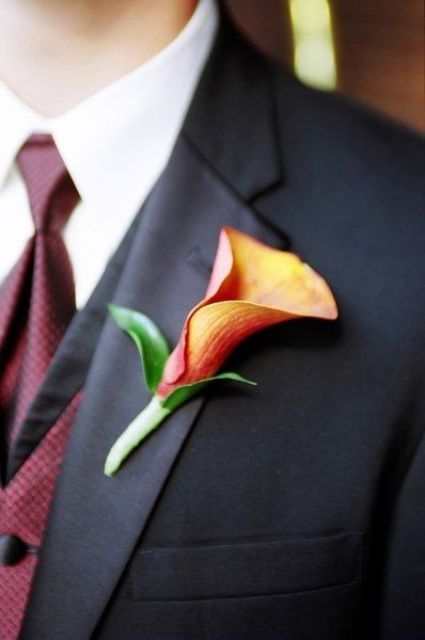 an orange calla lily with leaves is a timeless and cool wedding boutonniere for a bold fall groom's look