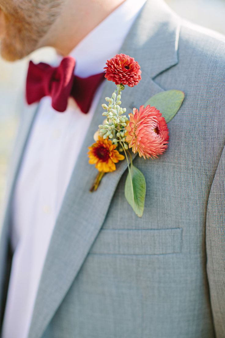 a bright fall wedding boutonniere with red and yellow blooms and some leaves is a stylish solution for a fall wedding