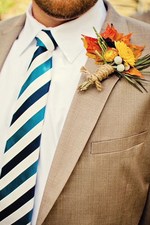 a bright wedding boutonniere with orange and yellow leaves, yellow and orange blooms and greenery is amazing