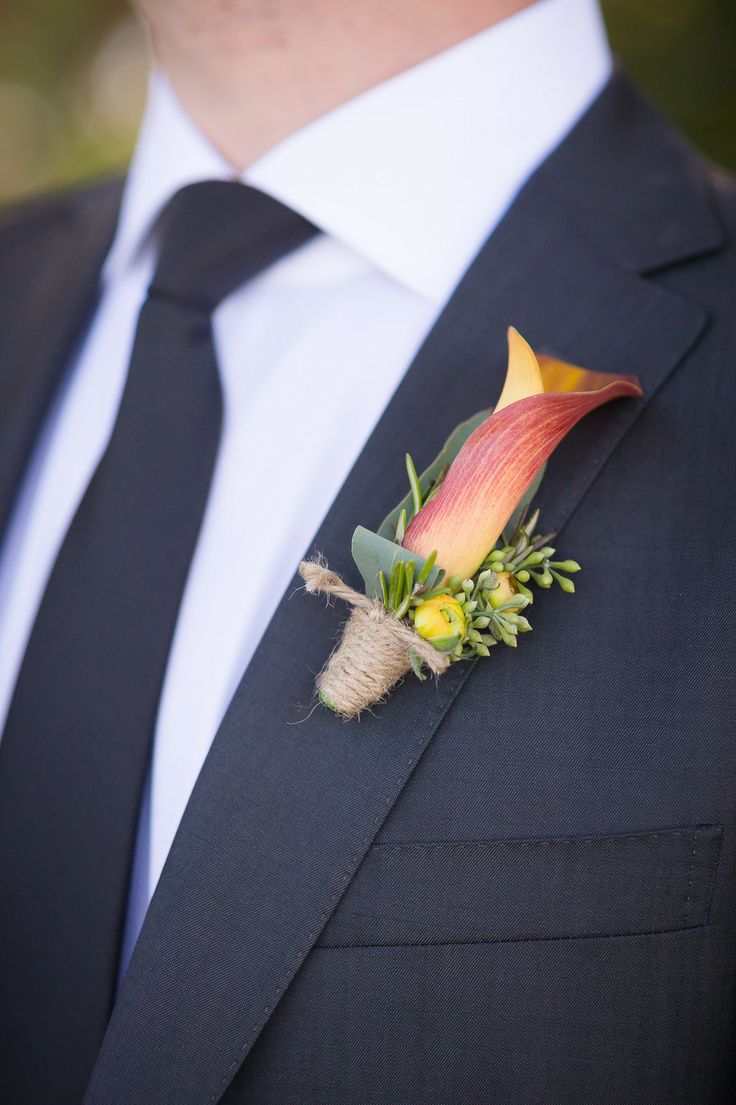 a refined wedding boutonniere with an orange calla lily, yellow blooms and berries and twine wrap for an elegant groom's look