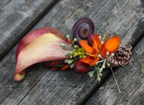 a bright wedding boutonniere with a burgundy calla lily and bright blooms plus greenery is wow