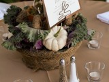 a rustic fall centerpiece of a bowl wrapped with burlap, soem veggies and a candle plus a large card on top
