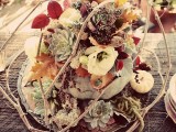 a super creative and textural wedding centerpiece of veggies, succulents, fall leaves and blooms plus some twigs on top