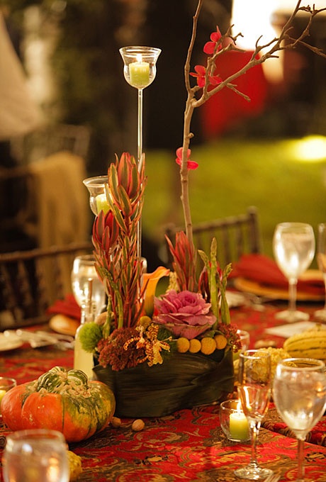 a bright fall wedding centerpiece with greenery and lush colorful flowers, pumpkins and candles