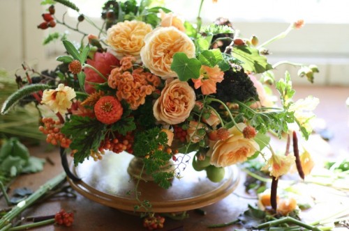 a fine art fall wedding centerpiece or orange, red and peachy blooms, greenery and foliage is lovely for fall