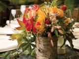 a fall wedding centerpiece of bright blooms and greenery in a stump is a cool woodland or rustic fall centerpiece