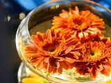 a glass bowl with bright floating blooms is a simple and chic fall wedding centerpiece