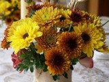a bright rustic fall wedding centerpiece of mustard and lemon blooms and greenery is cute