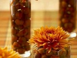 jars and tall glasses with nuts and acorns and bright blooms on top will compose a lovely and unusual fall wedding centerpiece