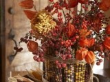 a bold and dried fall wedding centerpiece of corn cobs, dried blooms and some berries is simple and won’t wither