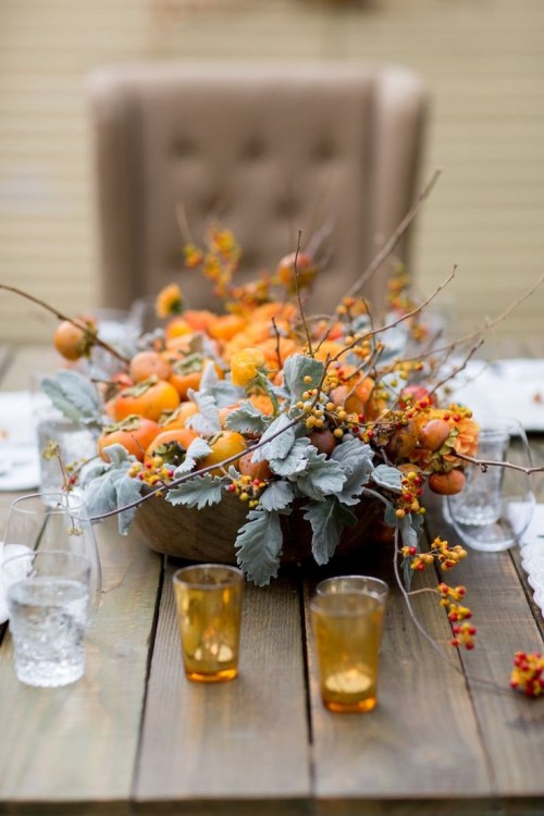 a wooden bowl with pale foliage, fruits and branches with berries is a simple and cool rustic fall wedding centerpiece