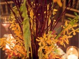 a bright and textural fall flower and branches centerpiece surrounded with candles is a classic idea for a fall wedding
