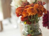 a jar with bold fall blooms and twine is very cool and chic and is easy to DIY for a fall wedding